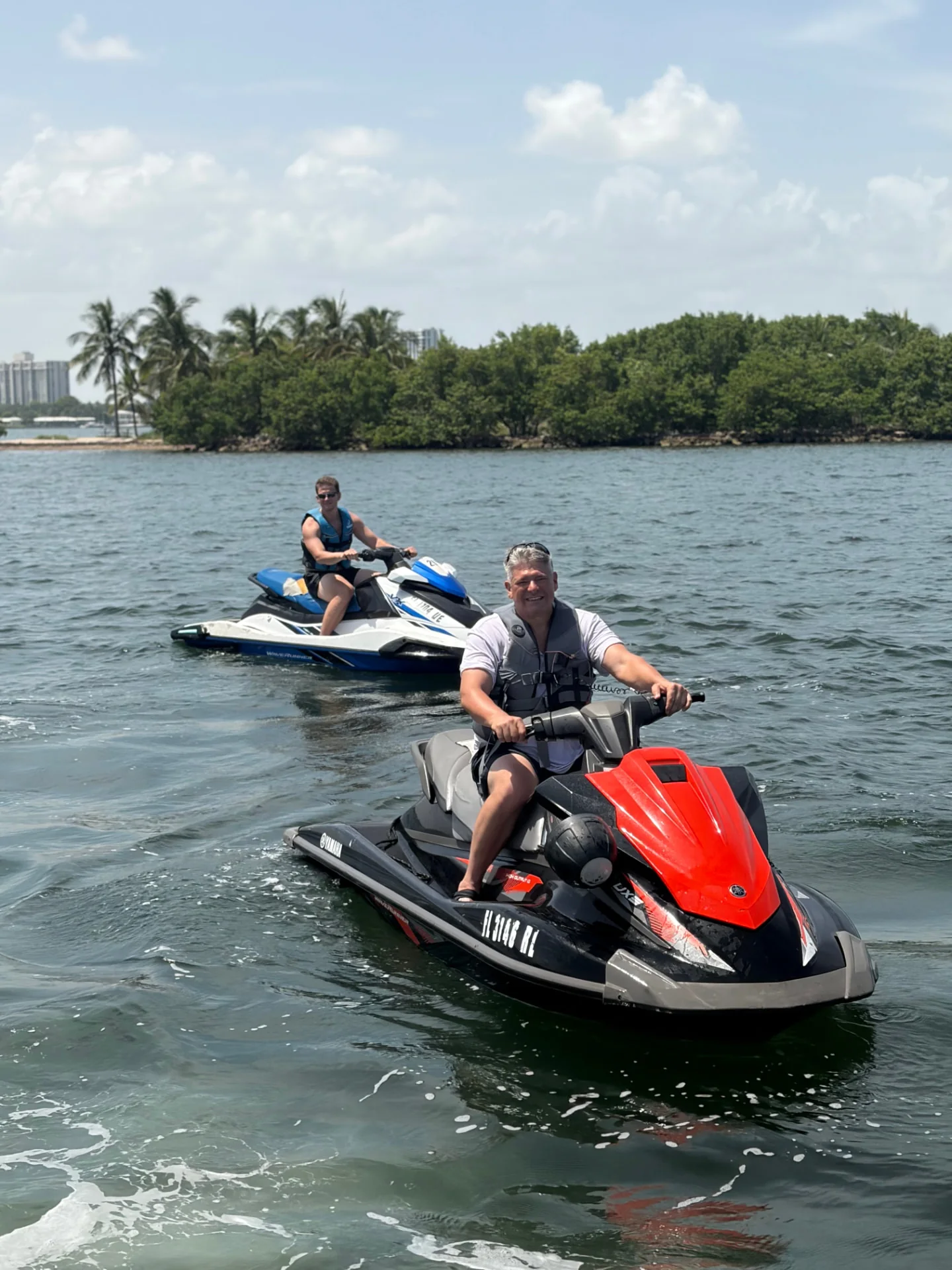Two riders enjoying red and blue Jet Skis on open Miami water